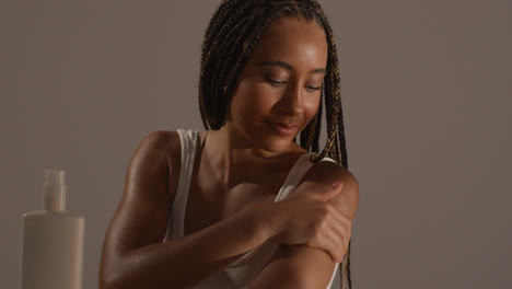 Studio-Skincare-Beauty-Shot-Of-Young-Woman-With-Long-Braided-Hair-Putting-Moisturiser-Onto-Arm-And-Shoulder-2